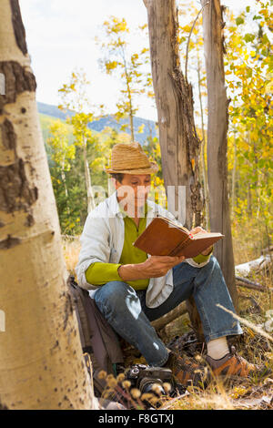 Man reading book in autumn forest Stock Photo