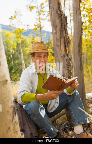 Man reading book in autumn forest Stock Photo