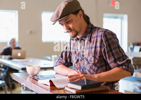 Caucasian student reading in cafe Stock Photo