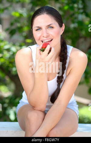 Caucasian woman eating strawberry outdoors Stock Photo