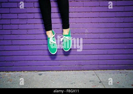 Asian woman jumping near brick wall Stock Photo
