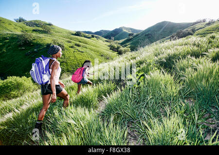 Black mother and daughter walking on rural hillside Stock Photo