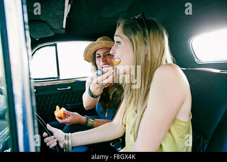 Woman feeding friend in vintage car Stock Photo