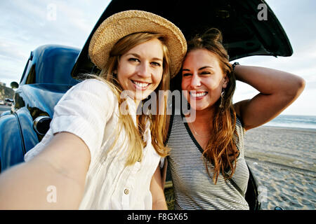 Women taking selfie in vintage car on beach Stock Photo