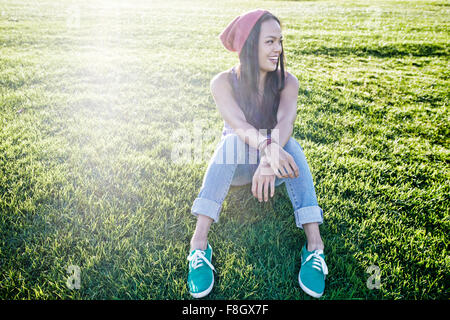 Asian woman sitting in grass Stock Photo