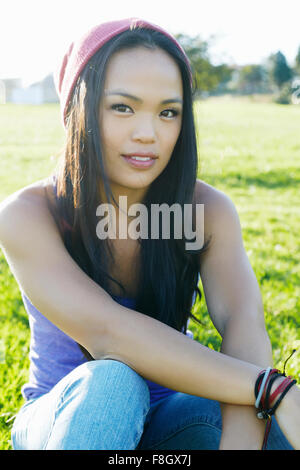 Asian woman sitting in grass Stock Photo