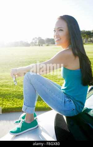 Asian woman sitting on car Stock Photo