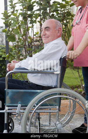 Hispanic nurse pushing patient in wheelchair Stock Photo