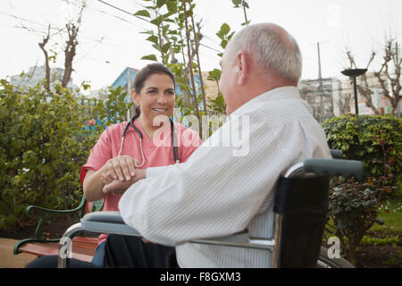 Hispanic nurse comforting patient in wheelchair Stock Photo