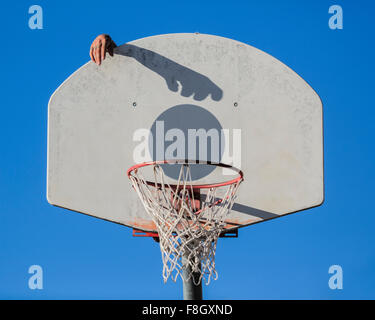 Caucasian man dunking basketball shadow in hoop Stock Photo