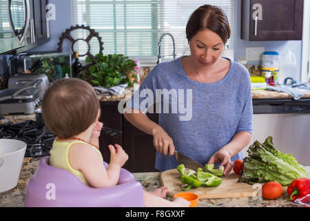 Mixed race mother chopping vegetables with daughter in kitchen