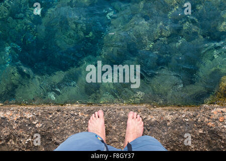 Caucasian man standing on rock wall over water Stock Photo