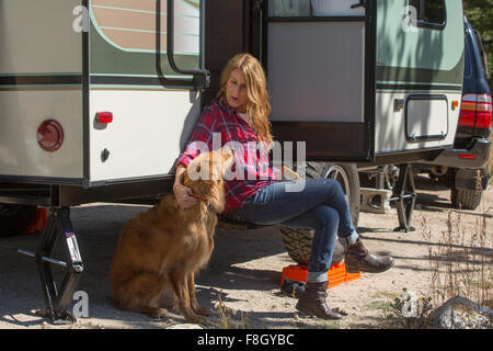 Caucasian woman petting dog at trailer Stock Photo