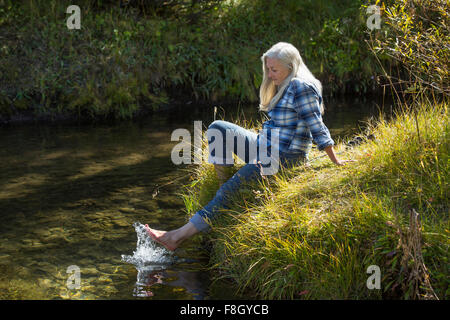 Caucasian woman splashing feet in river Stock Photo