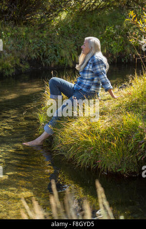 Caucasian woman dipping feet in river Stock Photo