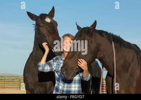 Caucasian rancher smiling with horses Stock Photo