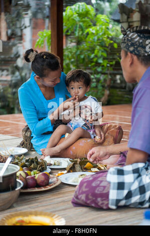 Asian mother feeding son on woven mat Stock Photo