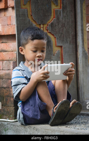 Asian boy using cell phone on front step Stock Photo