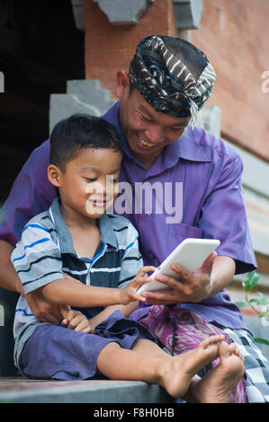 Asian father and son using cell phone outdoors Stock Photo