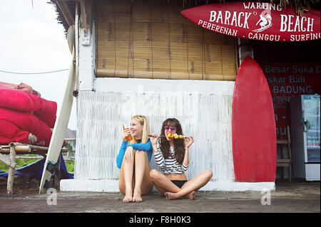 Caucasian women eating at surf hut on beach Stock Photo