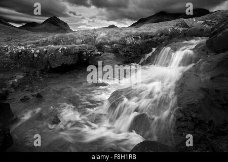 Waterfall over rocks in rural landscape Stock Photo