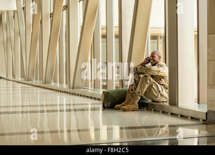 African American soldier talking on cell phone in airport Stock Photo