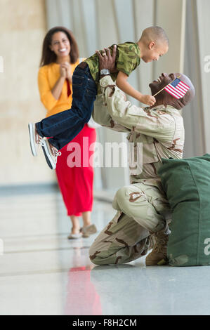 African American soldier greeting family in airport Stock Photo