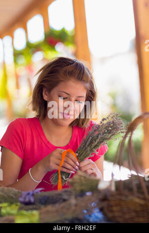 Mixed race girl tying bundle of flowers