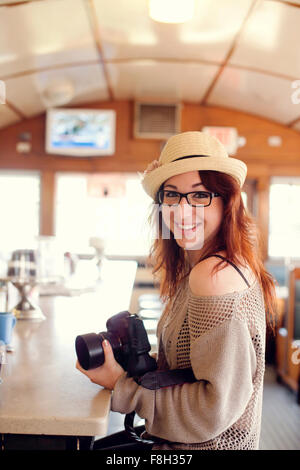 Caucasian woman holding camera in restaurant Stock Photo