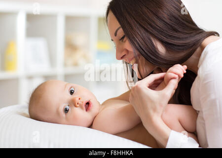 Happy mother playing with baby son in bedroom Stock Photo
