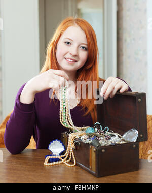 portrait of  red-headed teen girl looks jewelry in treasure chest Stock Photo