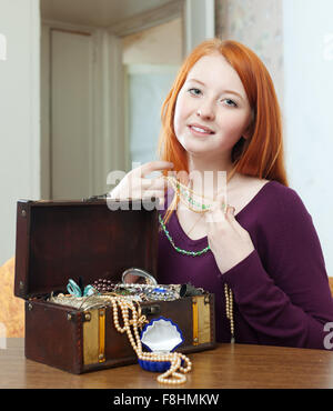 red-headed girl looks jewelry in treasure chest Stock Photo