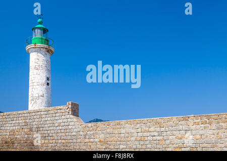 White lighthouse tower on stone pier. Entrance to Propriano, Corsica island, France Stock Photo