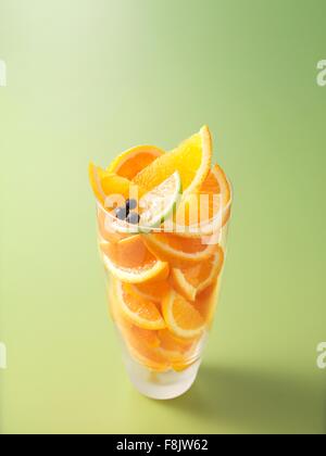 Ingredients in drinking glass for orange, lime and juniper berry fruit juice Stock Photo