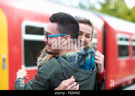 Heterosexual couple hugging at railway station, smiling Stock Photo