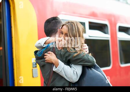 Heterosexual couple hugging at railway station Stock Photo