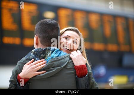 Heterosexual couple hugging at railway station, rear view Stock Photo