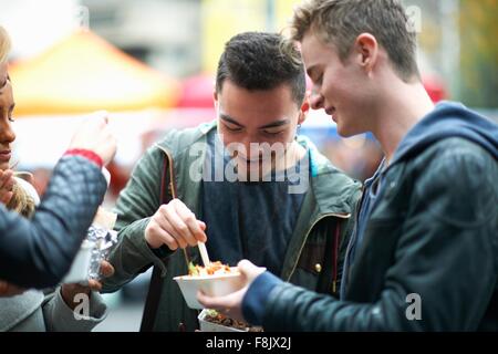 Group of young adults eating takeaway food, outdoors Stock Photo