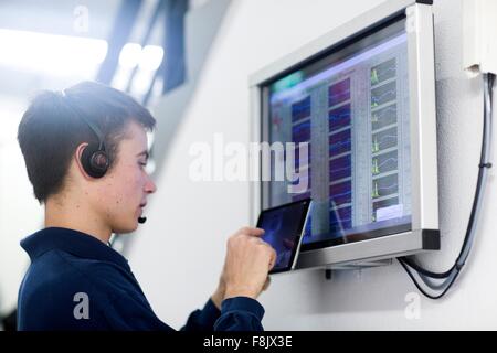Low angle side view of young man wearing headset using digital tablet Stock Photo