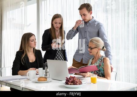 Colleagues at table having breakfast meeting looking at paperwork Stock Photo