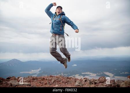 Young man jumping for joy at the summit of South Sister volcano, Bend, Oregon, USA Stock Photo