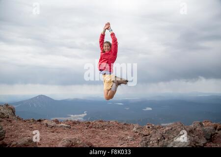 Young woman jumping for joy at the summit of South Sister volcano, Bend, Oregon, USA Stock Photo