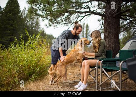 Young couple petting dog at campsite, Lake Tahoe, Nevada, USA Stock Photo