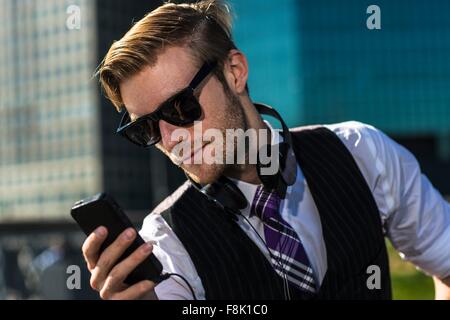 Young businessman in front of office reading smartphone texts, New York, USA Stock Photo