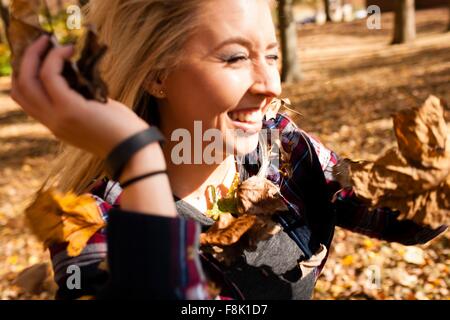 Young woman throwing autumn leaves in forest Stock Photo