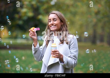 Young woman blowing bubbles in autumn park Stock Photo