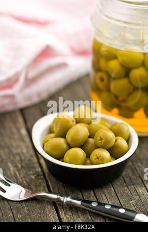 pitted green olives in bowl on wooden table Stock Photo