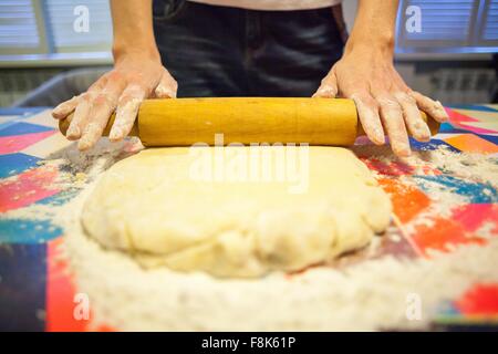 Close up of womans hands rolling dough on kitchen table Stock Photo