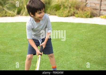 Front view of boy in garden playing cricket looking away smiling Stock Photo