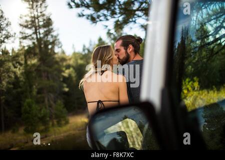 Rear view of romantic young couple kissing at riverside, Lake Tahoe, Nevada, USA Stock Photo